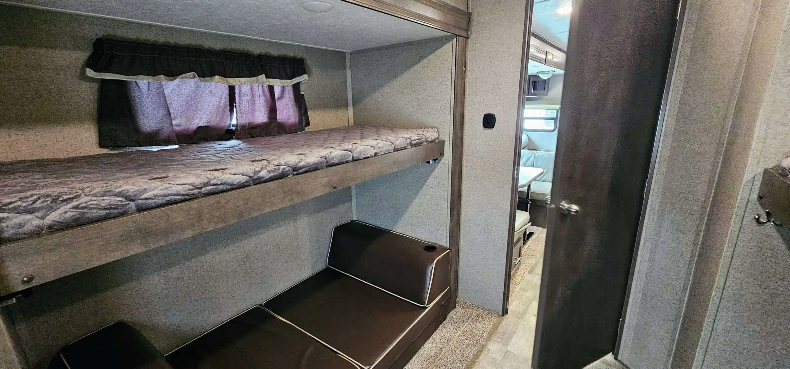 RV interior with bunk beds and dining area.