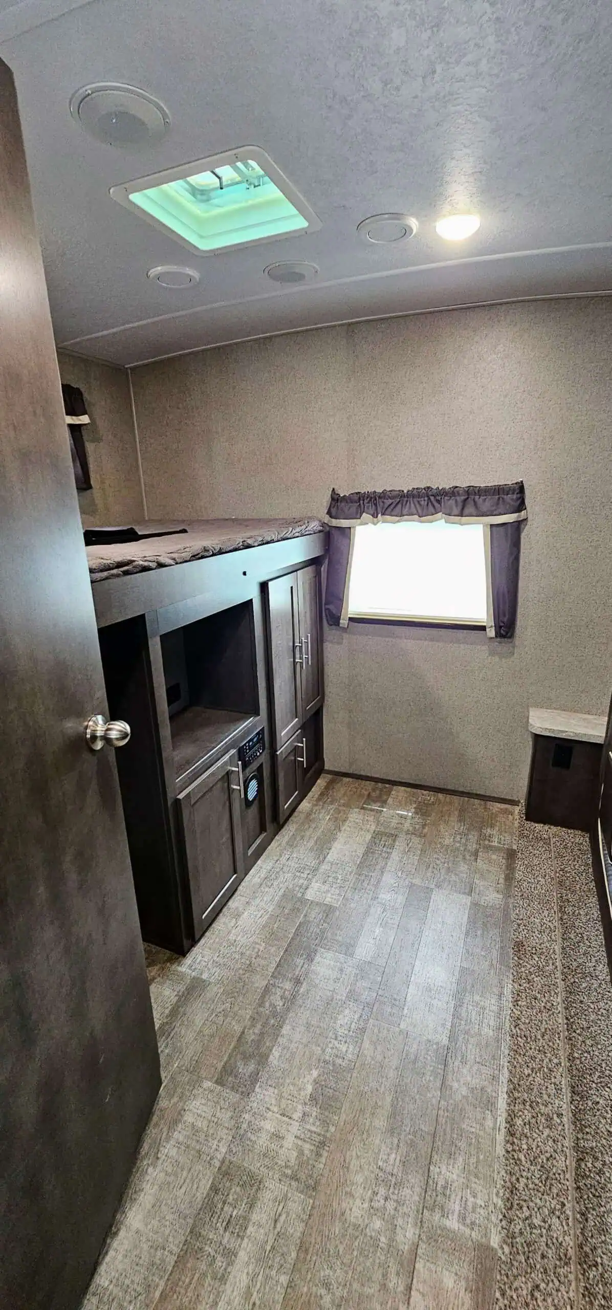 RV bunk bed interior with window and storage.