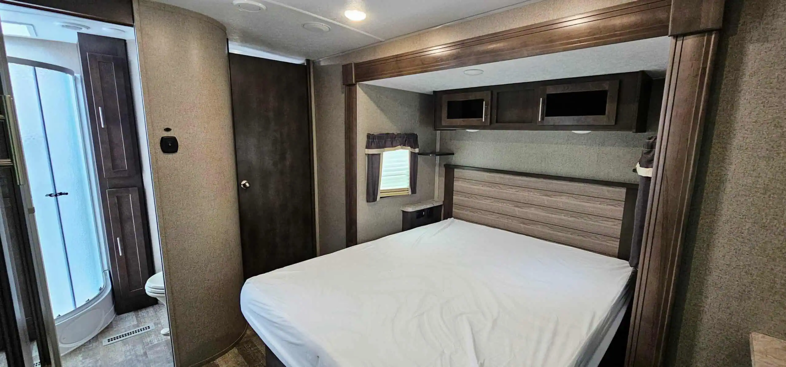 RV bedroom with bed and shower.