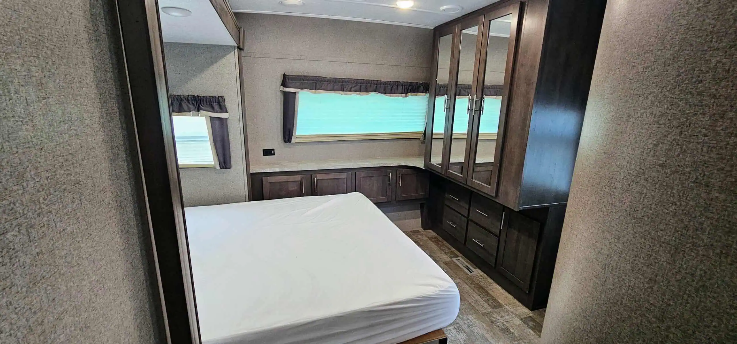 RV bedroom with a bed and wooden cabinets