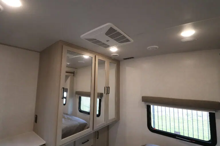 RV bedroom interior with cabinets and window.