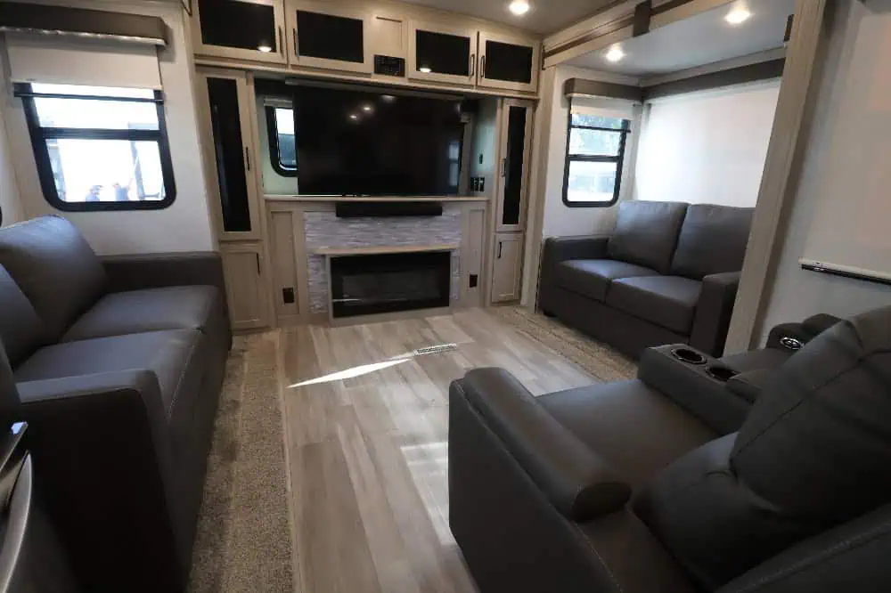 Modern RV living room with fireplace and large TV.